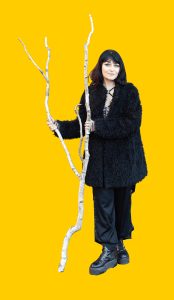 07 Gelber Hintergrund, davor ein Mensch im Portrait, in der Hand ein Birkenzweig