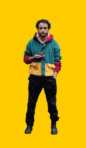12 Gelber Hintergrund, davor ein Mensch im Portrait, der eine mini-Schatztruhe in der Hand hält