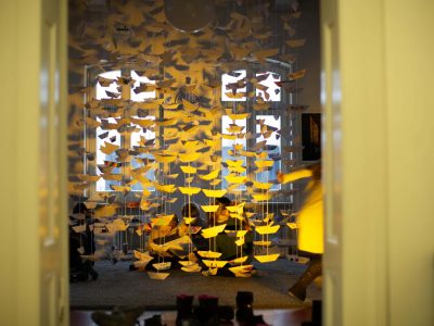 Viele gefaltete gelbe Papierbotte hängen von der Decke