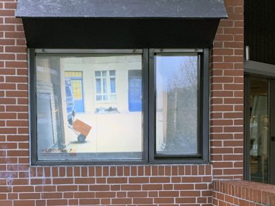 Fenster an dem ein Mensch mit Ziehwagen vorbeigeht
