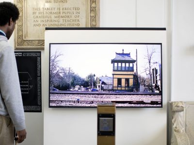 Mensch vor einem Bildschirm mit dem Bild eines Stellwerks