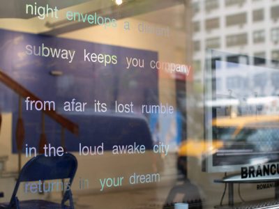 Schrift auf dem Fenster dahinter ein Raum mit blauer Wand